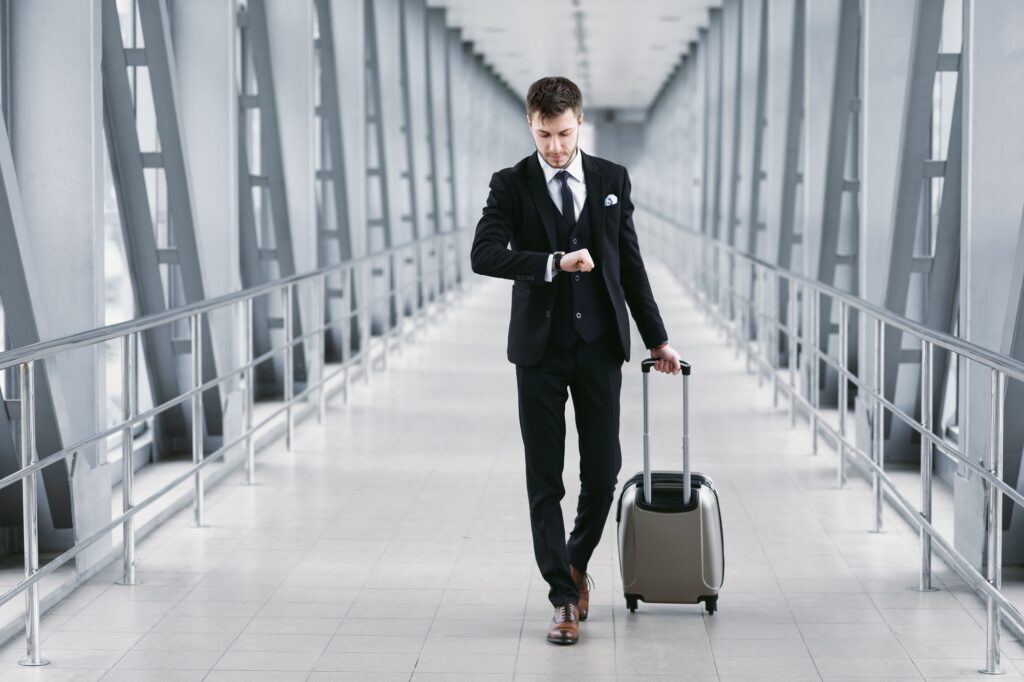 Adult business man standing in airport with suitcase