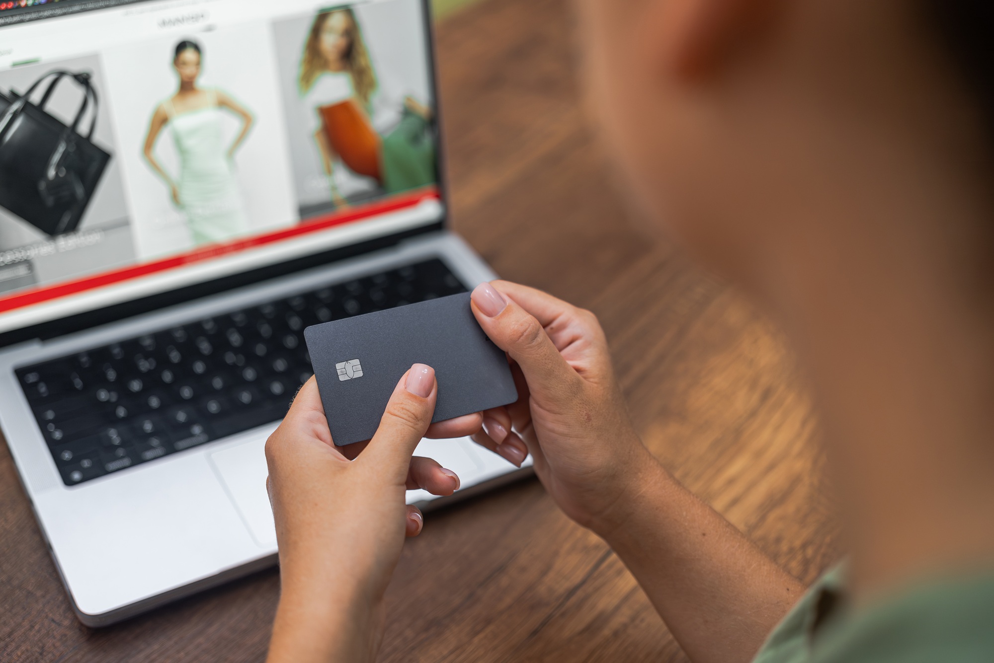 hands hold credit card against laptop screen online fashion clothing website, online shopping.